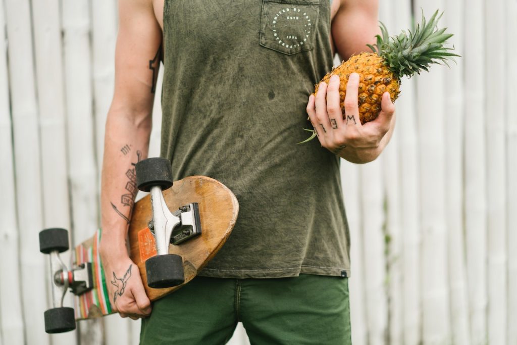 Man delivering a pineapple while carrying a skateboard